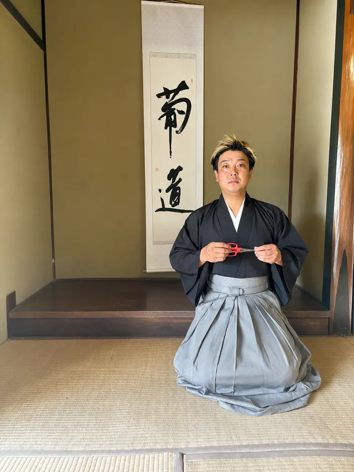 紋付き袴姿で、掛け軸「葡道」の前に正座する代表